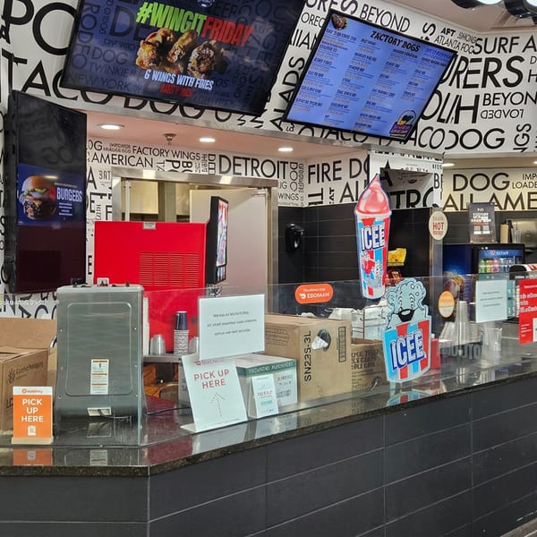 Fast-food restaurant counter with digital menus, pickup signs, cardboard packaging, and a prominent ICEE frozen drink display.